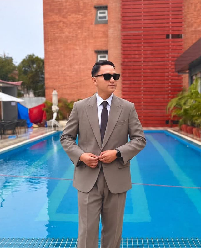 Milan Tamang in a suit beside a swimming pool